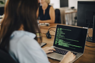 Female computer programmer working at desk in creative office