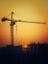 Silhouette cranes against clear sky during sunset