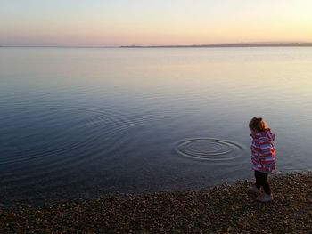 Boy standing at beach during sunset