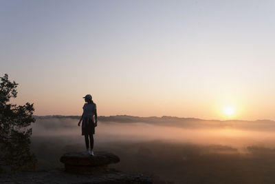 Silhouette of girl hiking on mountain top at sunrise