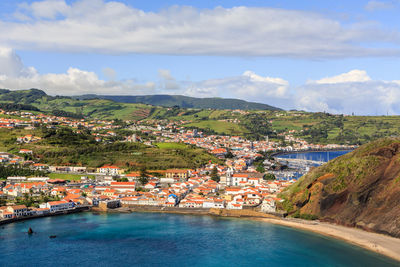 Aerial view of townscape by sea against sky