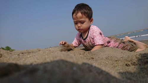 Full length of boy on sand against clear sky