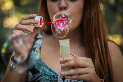 Midsection of woman holding bubbles