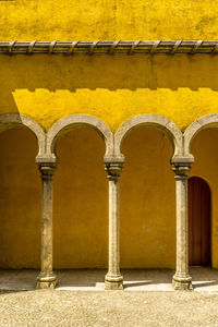 Three pillars against yellow wall.