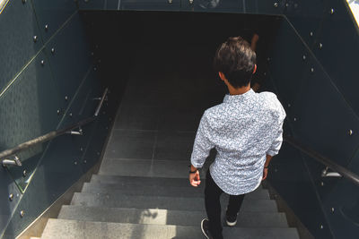 Rear view of man walking on staircase