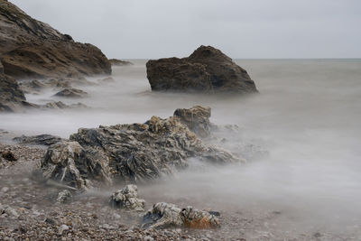 Scenic view of rocks in sea against sky