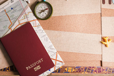 Directly above shot of passport and map by compass on table