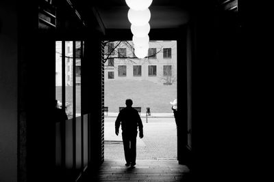 Silhouette of man walking out of building