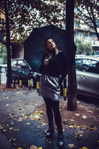 Full length of woman standing on car during rainy season