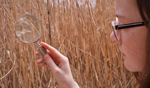 Close-up portrait of woman holding eyeglasses on plant