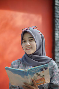 Portrait of smiling young woman standing against sky