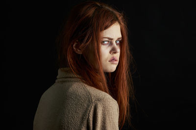 Young woman standing against black background