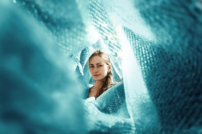 Portrait of beautiful woman surrounded with blue textiles