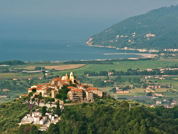 High angle view of houses on field by sea against sky