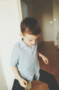 Boy standing with legs apart at home