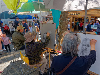 Rear view of people sitting at market stall in city