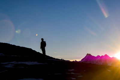 Silhouette man standing on rock against sea at sunset