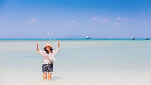 Full length of woman standing at beach against sky