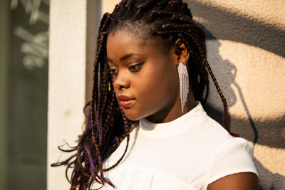 Close-up of young woman looking away while standing against wall