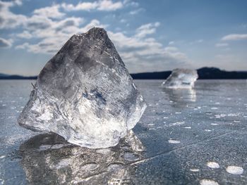 Ice floe at frozen surface with many reflection, blue sky in background. winter frozen lake