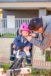 Father adjusting cycling helmet for daughter in park