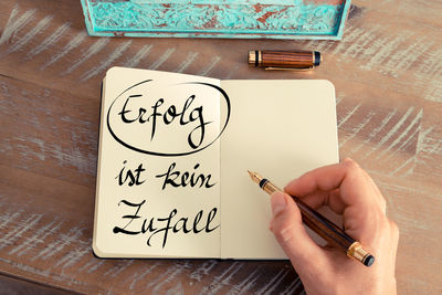 Cropped hand of person writing in book