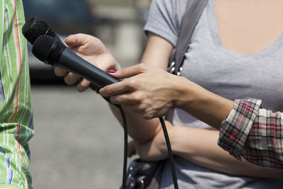 Cropped hands of female journalist interviewing man on street