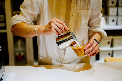 Midsection of man preparing drink at table