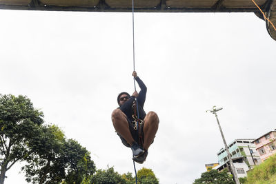 Low angle view of man jumping against sky