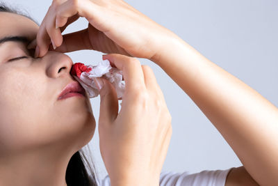 Close-up of woman holding tissue on bleeding nose