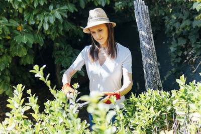 Young woman wearing hat standing against plants