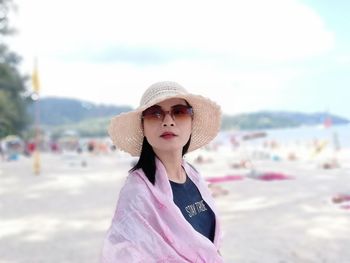 Portrait of woman standing at beach against sky