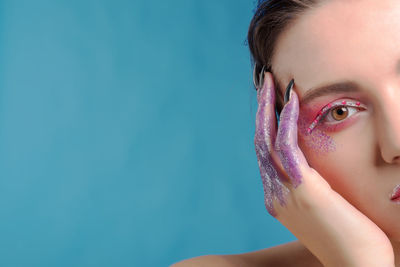 Close-up portrait of beautiful woman against blue background