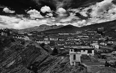 Buildings on mountains against cloudy sky in village