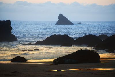 Rock formation on sea against sky during sunset