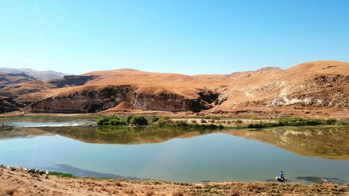 Scenic view of lake and mountains against clear blue sky