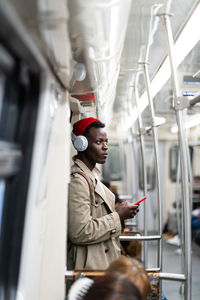 Young man listening music while standing in train