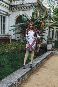 Portrait of young woman standing against built structure