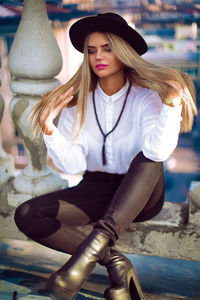 Young woman looking away sitting on retaining wall