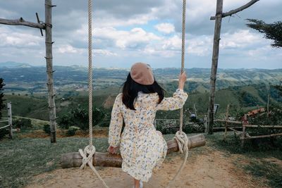 Rear view of woman sitting on swing