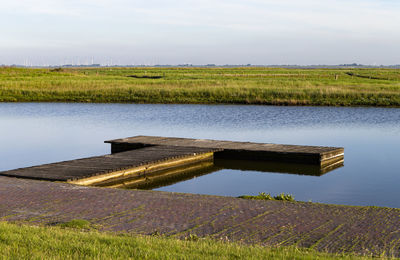 Built structure on field by lake against sky