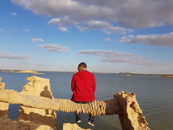 Rear view of man looking at sea against sky