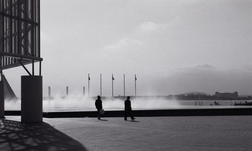 Men on water in city against sky