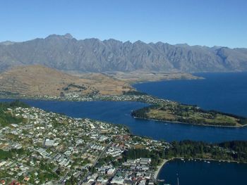 Aerial view of sea and mountains against clear blue sky