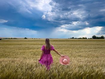 Rear view of woman standing on field against sky