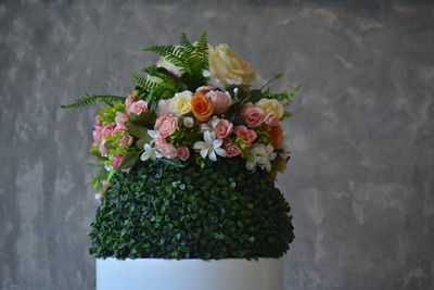 Cropped hand of woman with bouquet against wall