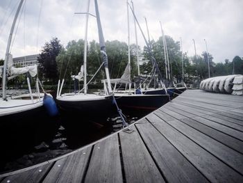 Boats moored at harbor against sky