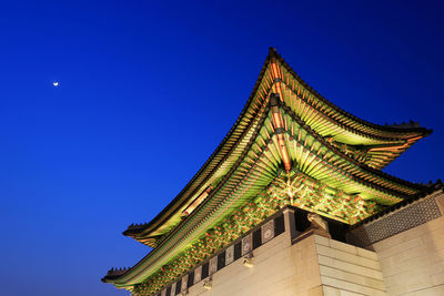 Low angle view of illuminated building against clear blue sky