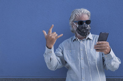 Portrait of man using mobile phone against blue wall