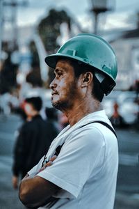Profile view of male worker wearing green hardhat at construction site